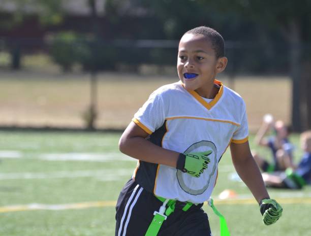 Enjoying the Game mixed race 9 year old boy loping on the flag football field, happy, autumn mouthguard stock pictures, royalty-free photos & images