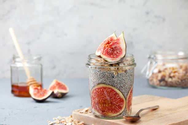chia pudding with figs healthy breakfast. chia pudding with figs, muesli in a glass jar on a gray concrete background eating chia seeds stock pictures, royalty-free photos & images