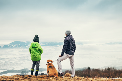Father with son and dog look together on winter mountain city panorame