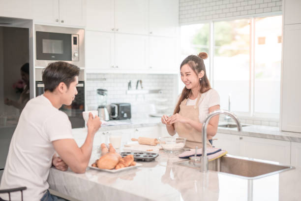 istock Man drinks coffee while a woman prepares a meal 860156586