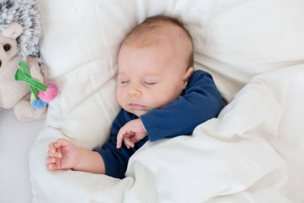 istock Cute newborn baby boy, lying in bed with cold 860161808