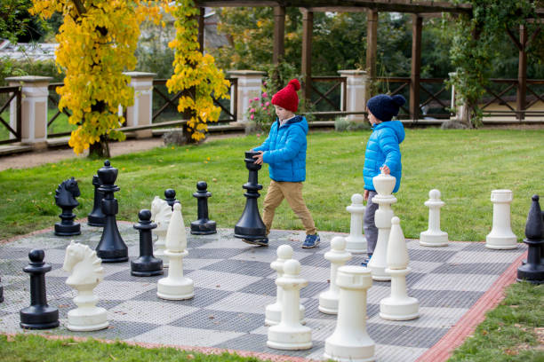 istock Two children, boy brothers, playing chess with huge figures in the park 860164546