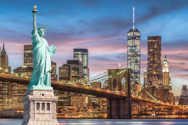 die statue of liberty und brooklyn bridge mit world trade center hintergrund dämmerung sonnenuntergang, wahrzeichen von new york city - famous place new york city new york state manhattan stock-fotos und bilder