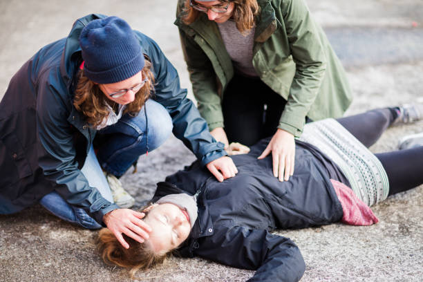 Two woman looking after unconscious woman stock photo