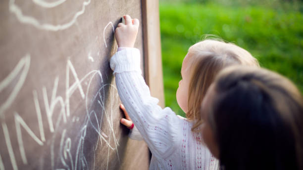 istock Toddler girl having fun outdoors, holding chalk and drawing. 860187414