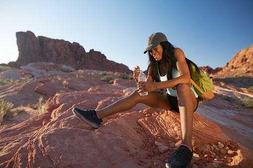 fit african american woman resting with water bottle during hike at valley of fire park