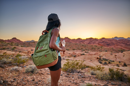 female african american hiker watching sunset in nevada desert at valley of fire