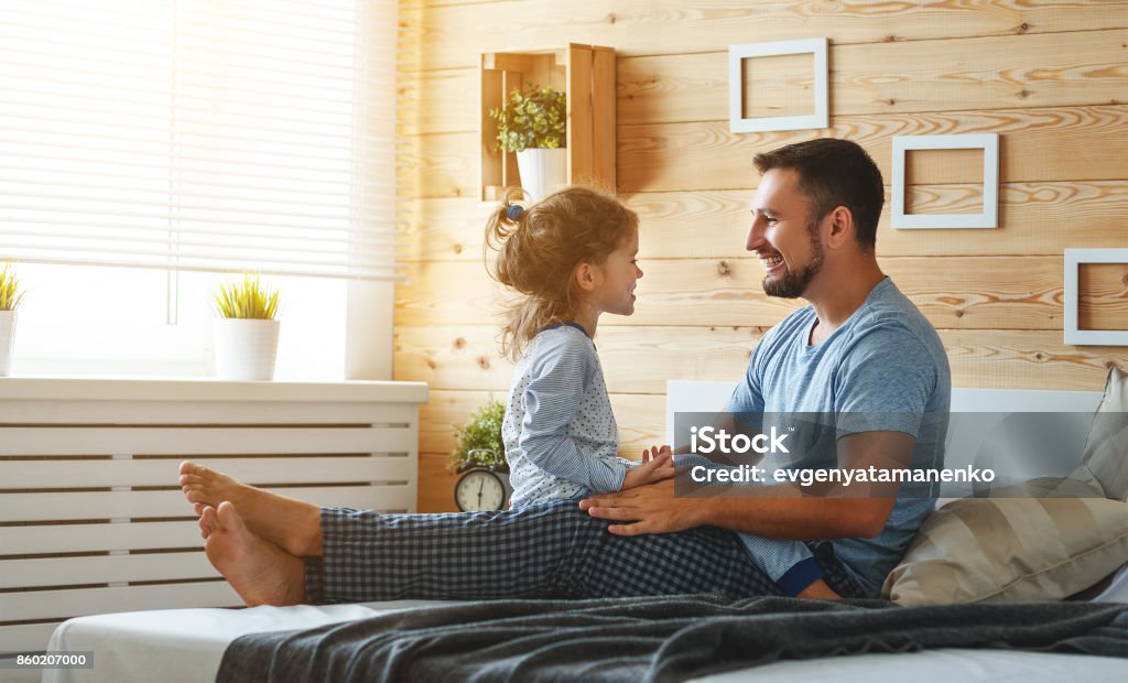 happy family father and   daughter reading book in bed happy family father and child daughter reading book in bed Adult Stock Photo