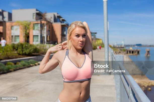 Young Blonde Woman Stretching Outside Before Jogging Stock Photo - Download Image Now