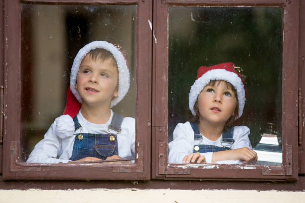 istock Two cute boys, brothers, looking through a window, waiting for Santa 860227786
