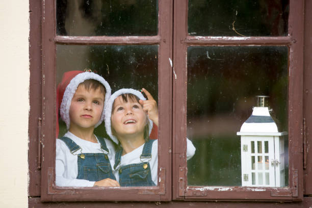 istock Two cute boys, brothers, looking through a window, waiting for Santa 860227850