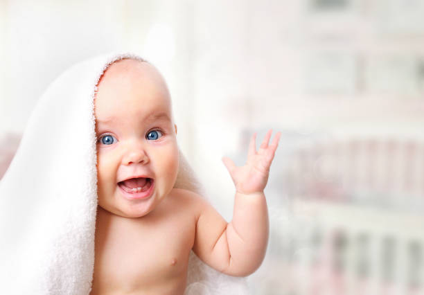 Baby in towel on blur background. Baby in bathroom towel background empty space. making a face photos stock pictures, royalty-free photos & images
