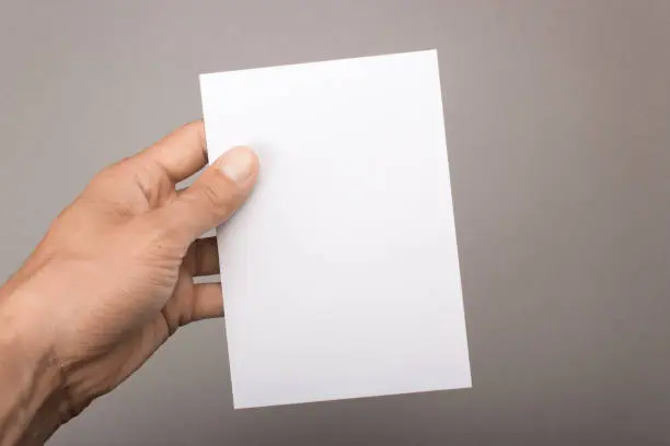 Blank postcard in hand on a gray background. Leaflet A6 mockup