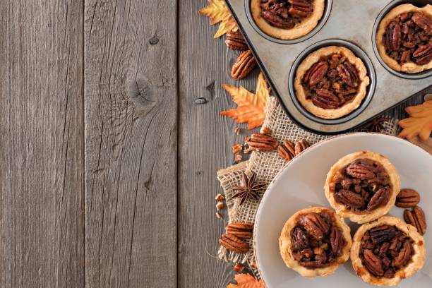 istock Autumn baking scene side border with pecan tarts over wood 860239480