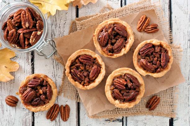 tartelettes de noix de pécan, au-dessus de la scène de tableau sur bois blanc rustique - tarte sucrée photos et images de collection