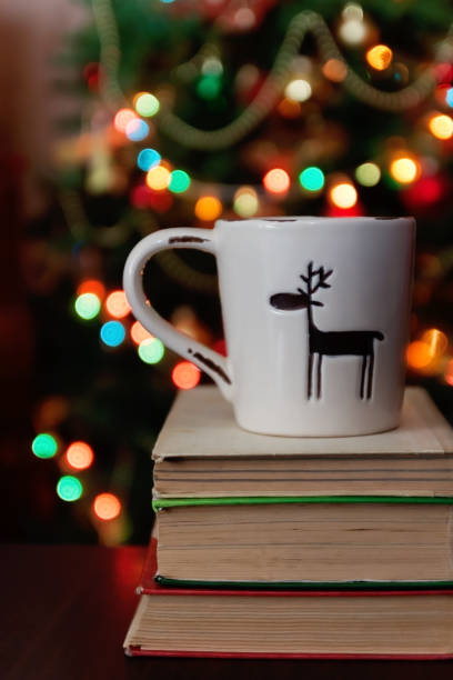 istock Christmas celebration with cup and gift box on books over bokeh and trees background 860240260