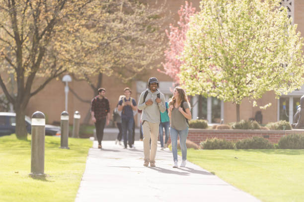 istock College students hang out in between classes on sidewalk, talking and smiling 860242644
