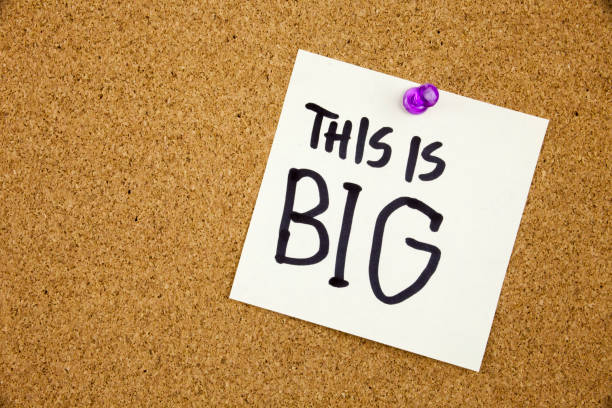 istock A yellow sticky note writing, caption, inscription Note paper with a text THIS IS BIG and black push pin on cork board. 860245936