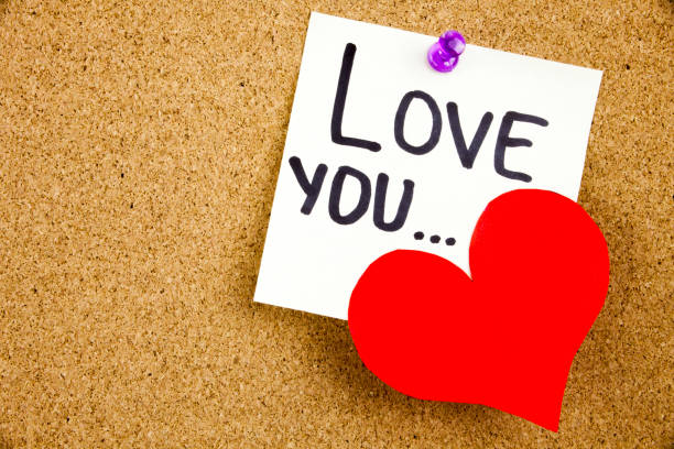 istock A yellow sticky note writing, caption, inscription Phrase LOVE YOU ... in black ext on a WHITE sticky note pinned to a cork notice board 860246502