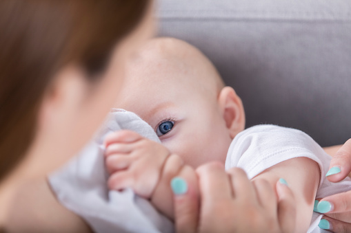 Adorable bebé de ojo azul Mira mamá durante la lactancia photo