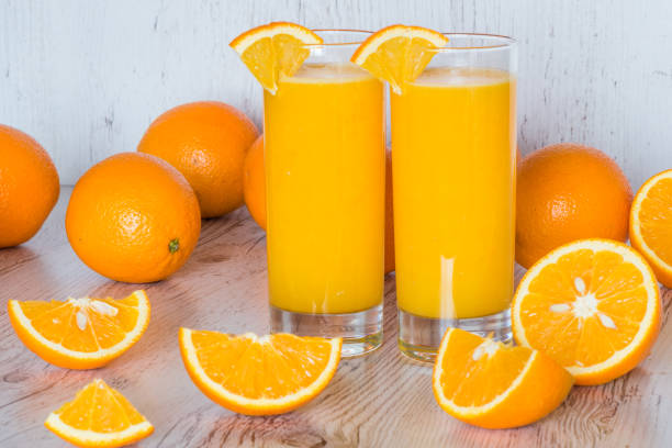 istock orange juice in glasses at light wooden background 860260232