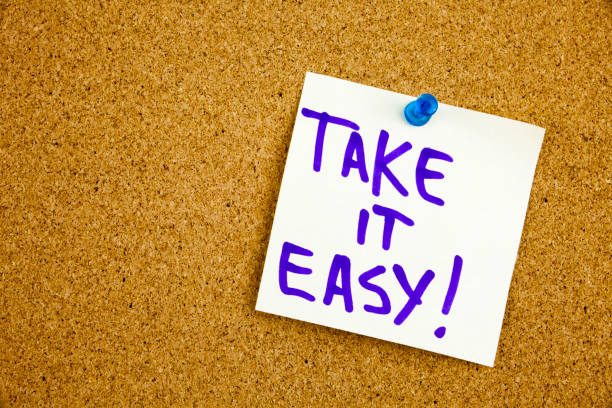 istock A yellow sticky note writing, caption, inscription take it easy, motivational lifestyle reminders against black ext on a colorful sticky note pinned to a cork notice board 860267564