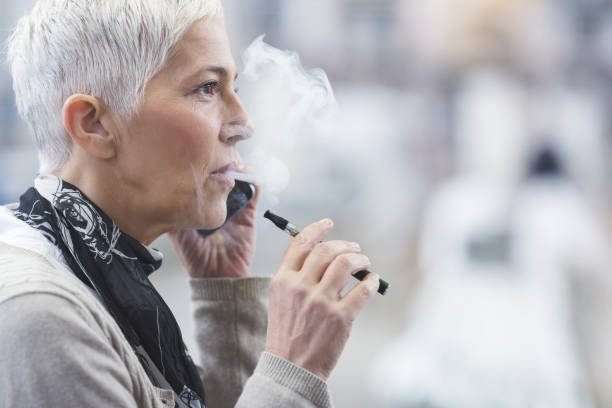 Senior female using electronic cigarette stock photo