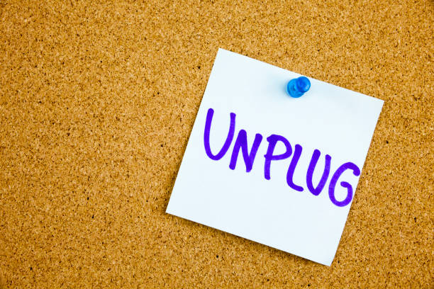 istock A yellow sticky note writing, caption, inscription unplug, motivational lifestyle reminders against black ext on a colorful sticky note pinned to a cork notice board 860267728