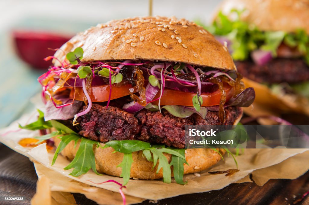 Tasty vegetarian beet burgers on wooden table Close-up of home made vegetarian red beet burgers on wooden table. American Culture Stock Photo
