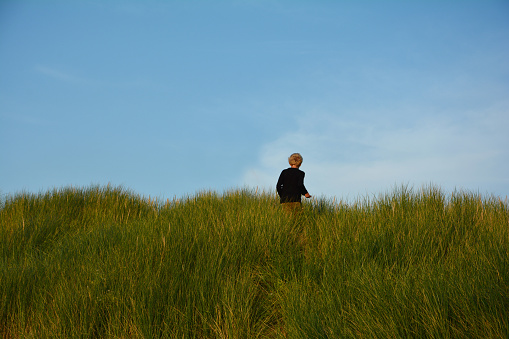 Small boy on top on a sandy dune, in the middle of the beach oat on the North Sea coast