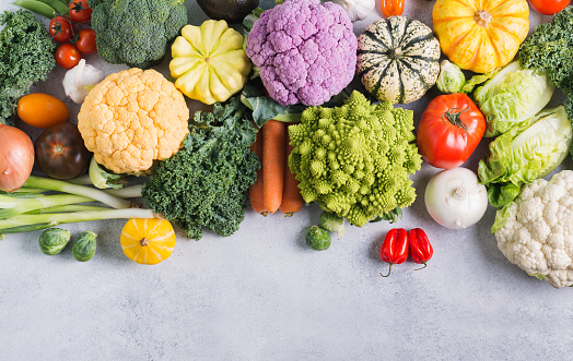 Top view of different colored rainbow vegetables on the light grey background, copy space for text below, selective focus
