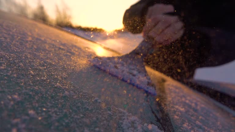 SLOW MOTION: Person scraping morning frost off a car window on winter morning
