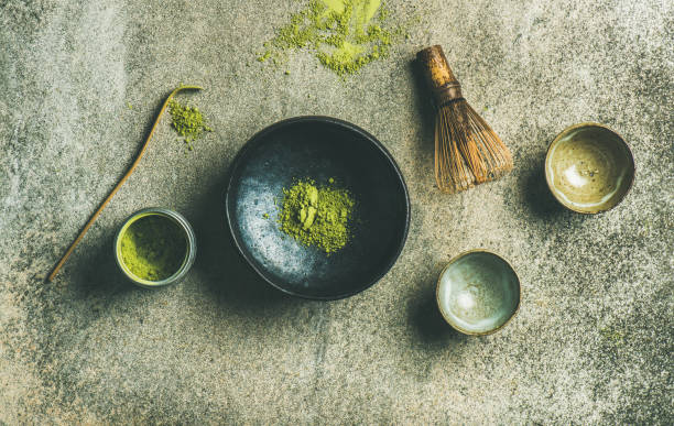 Japanese tools for brewing matcha green tea, grey concrete background Flat-lay of Japanese tools for brewing matcha tea. Matcha powder in tin can, Chashaku spoon, Chasen bamboo whisk, Chawan bowl and cups over concrete background, top view, horizontal composition above can drink high angle view stock pictures, royalty-free photos & images