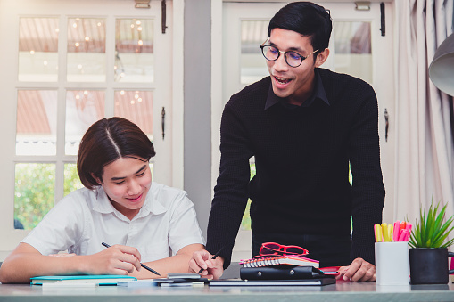 Education concept - Two students doing homework together and helping each other sitting in a table.