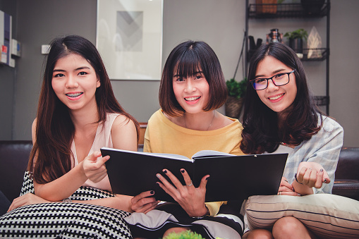 Group of young euphoric students.Happy young university students studying with books in library.