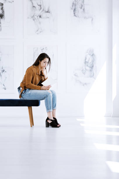 istock Young woman reading art guidebook 860320844