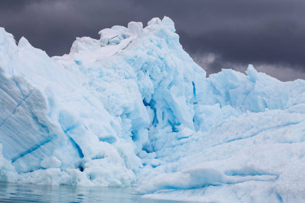 iceberg avec fond de nuage sombre - glacier antarctica crevasse ice photos et images de collection