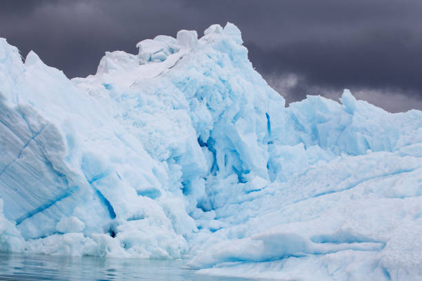 暗い雲の背景の氷山 - ice arctic crevasse glacier ストックフォトと画像