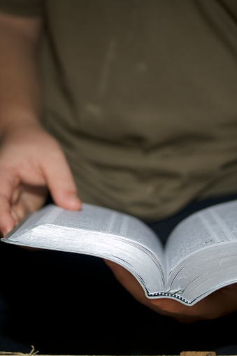 A young man reads the Bible. Holds an open book in his hands.