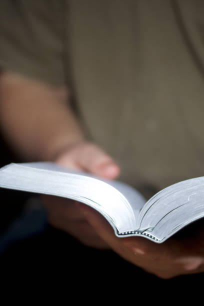 istock A young man reads the Bible. Holds an open book in his hands. 860322192