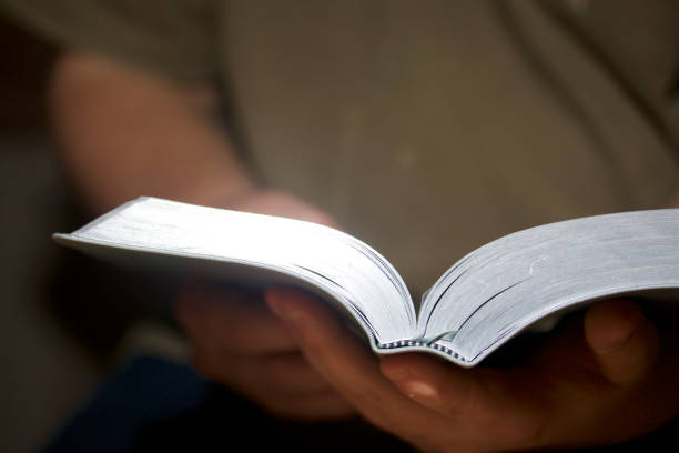 istock A young man reads the Bible. Holds an open book in his hands. 860322204