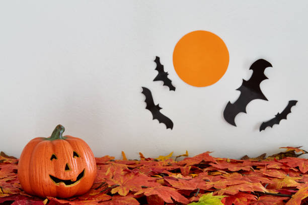 istock Happy Halloween pumpkin head jack lantern with bat and moon on leaves 860341990
