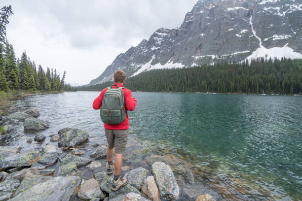 istock Young man hiker on rock above mountain lake 860351108