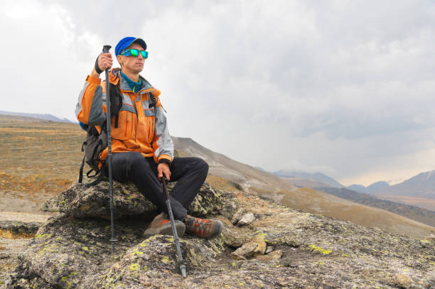 istock A lonely tourist with a backpack and in sunglasses is resting sitting on a rock 860366772