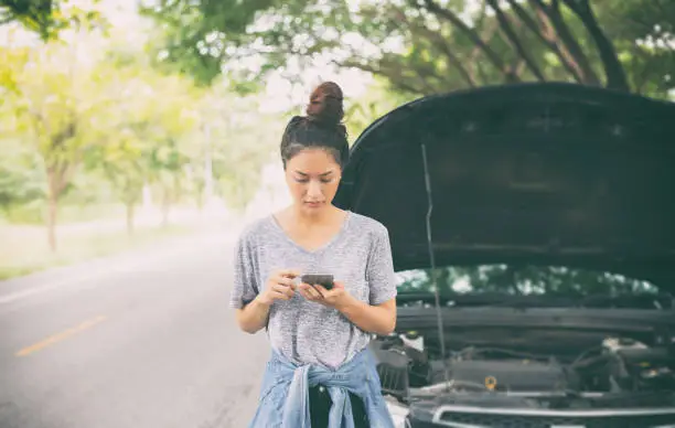 Photo of Asian woman using mobile phone while looking and Stressed man sitting after a car breakdown on street