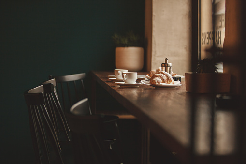 Coffee and croissants are served on a bar counter.