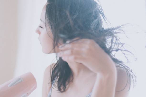 女人在家裡幹她的頭髮用吹風機 - 僅日本人 圖片 個照片及圖片檔