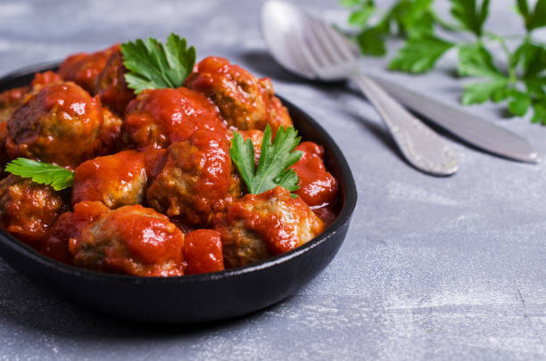 Traditional spicy meatballs in tomato sauce on concrete background. Selective focus.