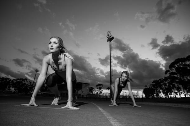 istock Female sprinter athletes getting ready to start a race on a tartan racetrack 860393182