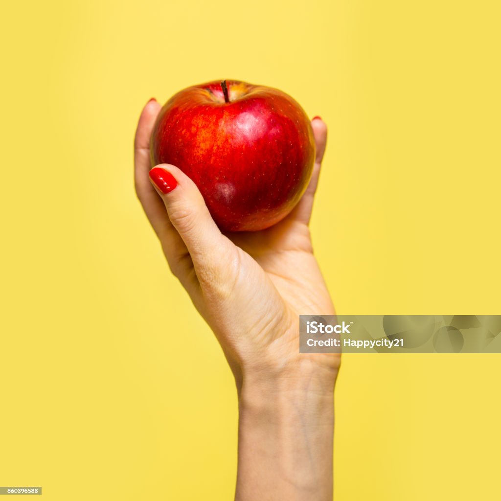An apple in a hand An apple in a hand over yellow background Apple - Fruit Stock Photo